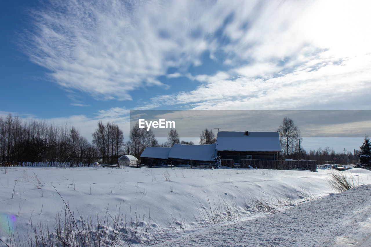 Houses on field against sky during winter