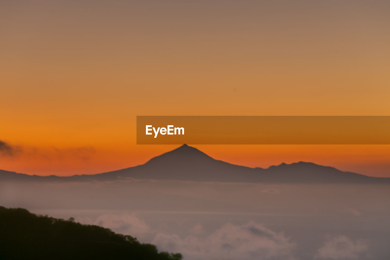 Scenic view of silhouette mountains against orange sky