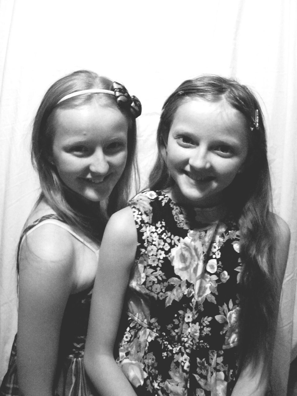 Portrait of smiling twin sisters against wall