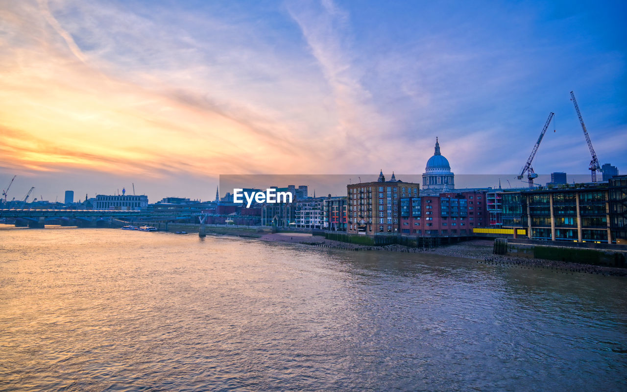 VIEW OF BRIDGE OVER RIVER AND BUILDINGS AGAINST SKY