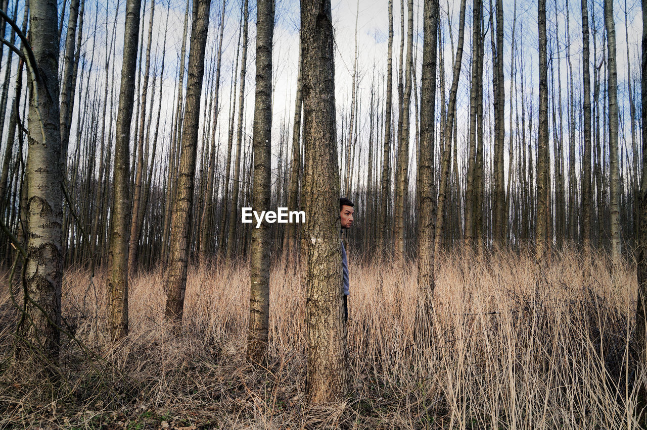 Man hiding behind tree