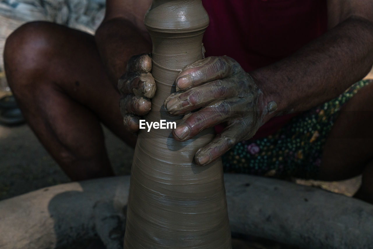 Midsection of man working on pottery wheel