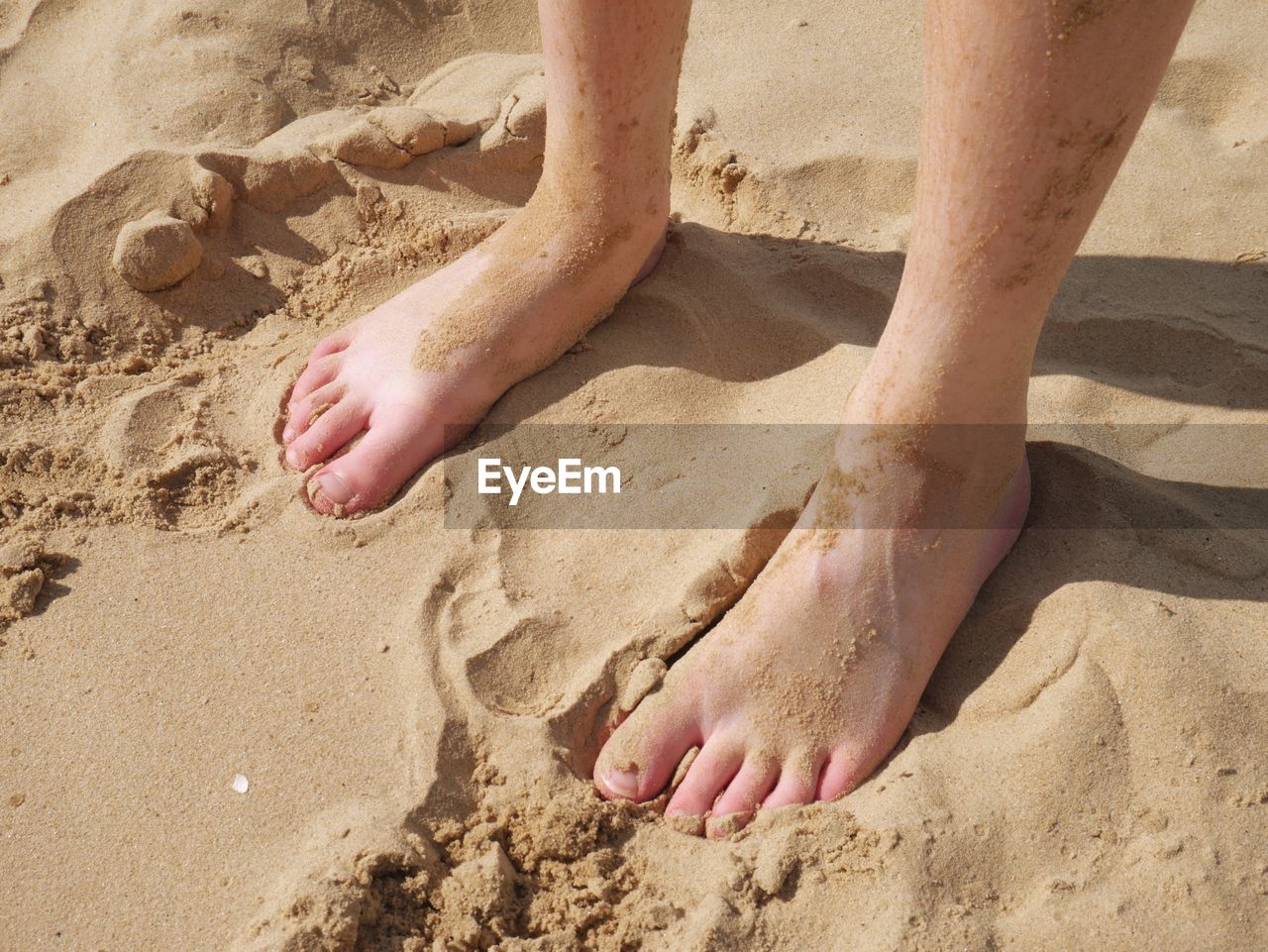 Close-up of feet in sand