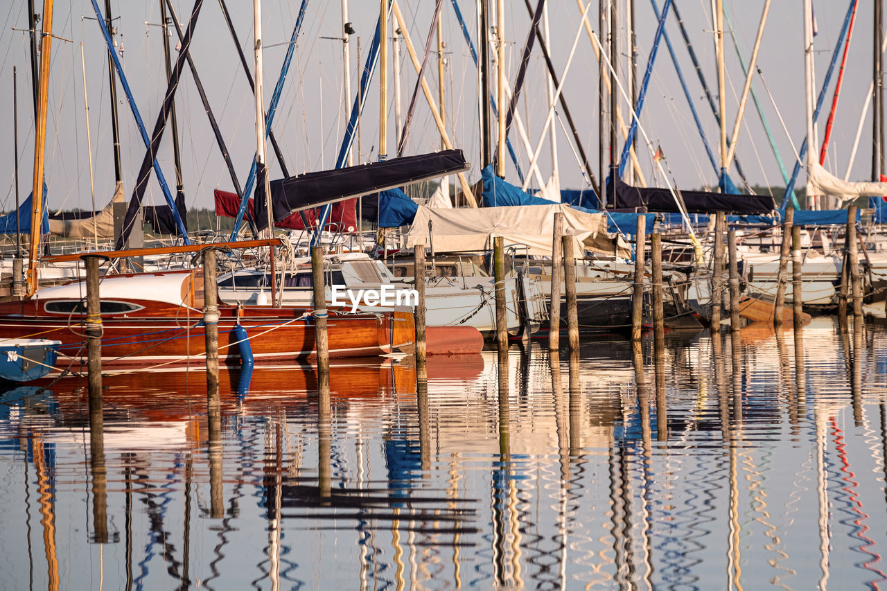 Moored sailboats in marina with reflections in the water