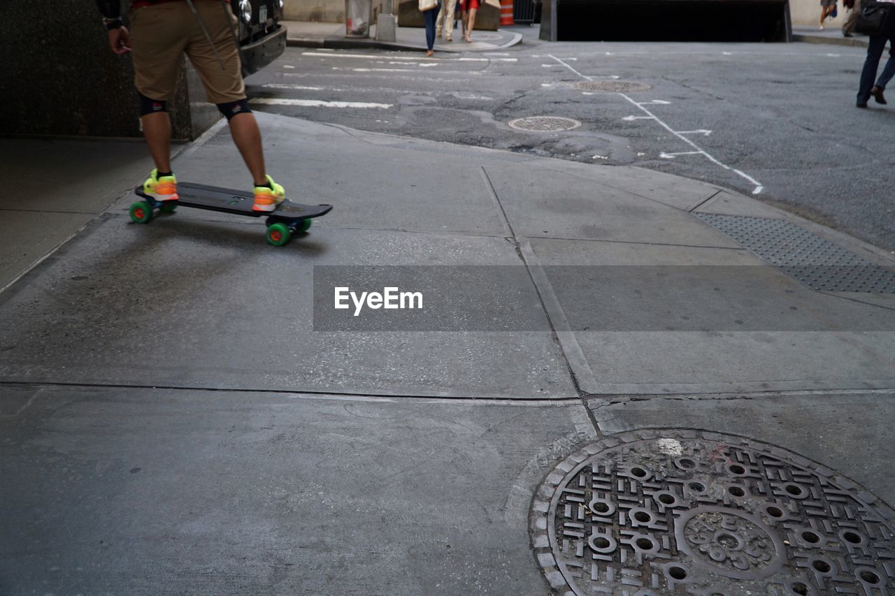 Low section of man skating on sidewalk in city