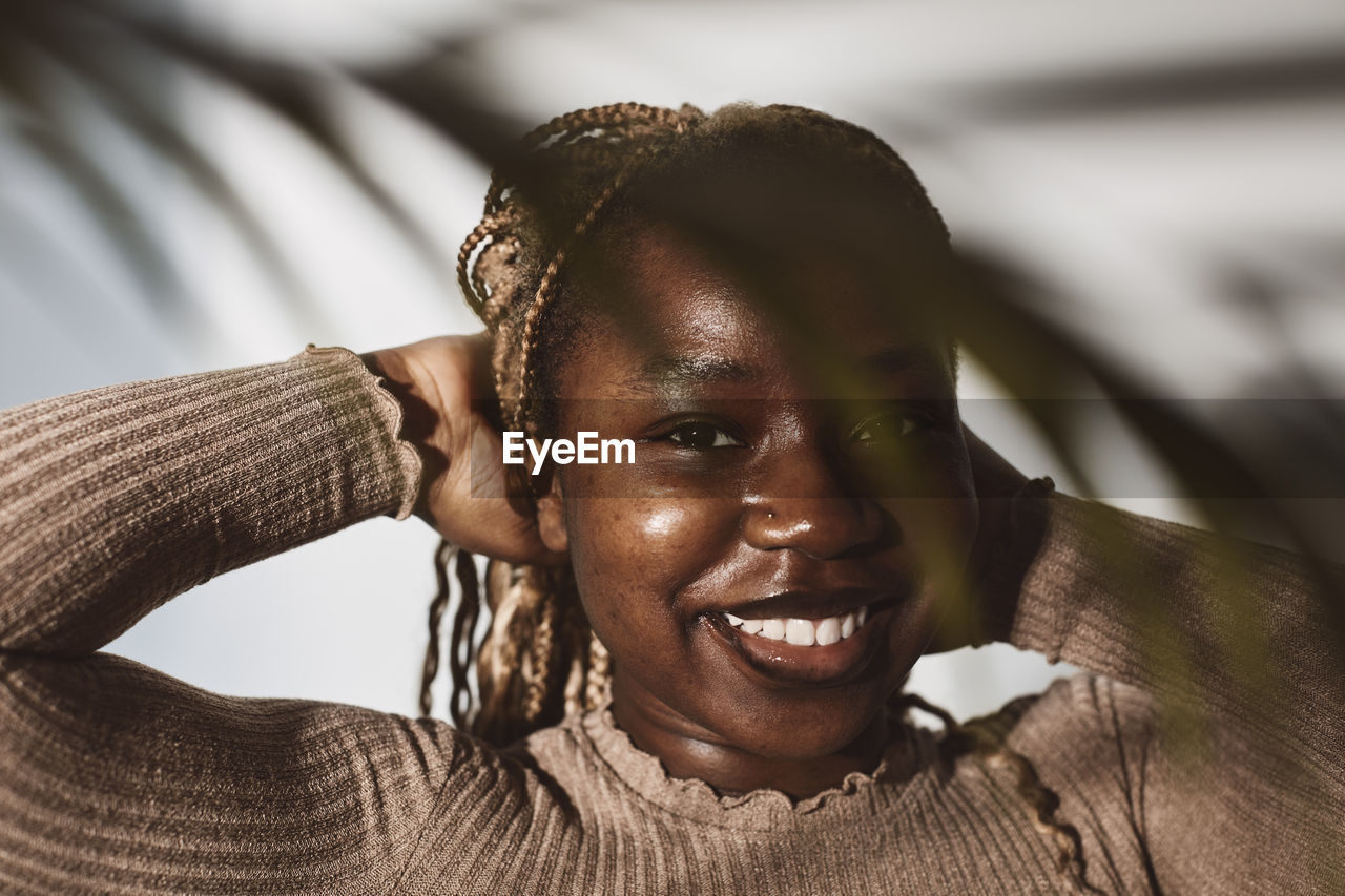 Smiling woman with hands behind head against white background