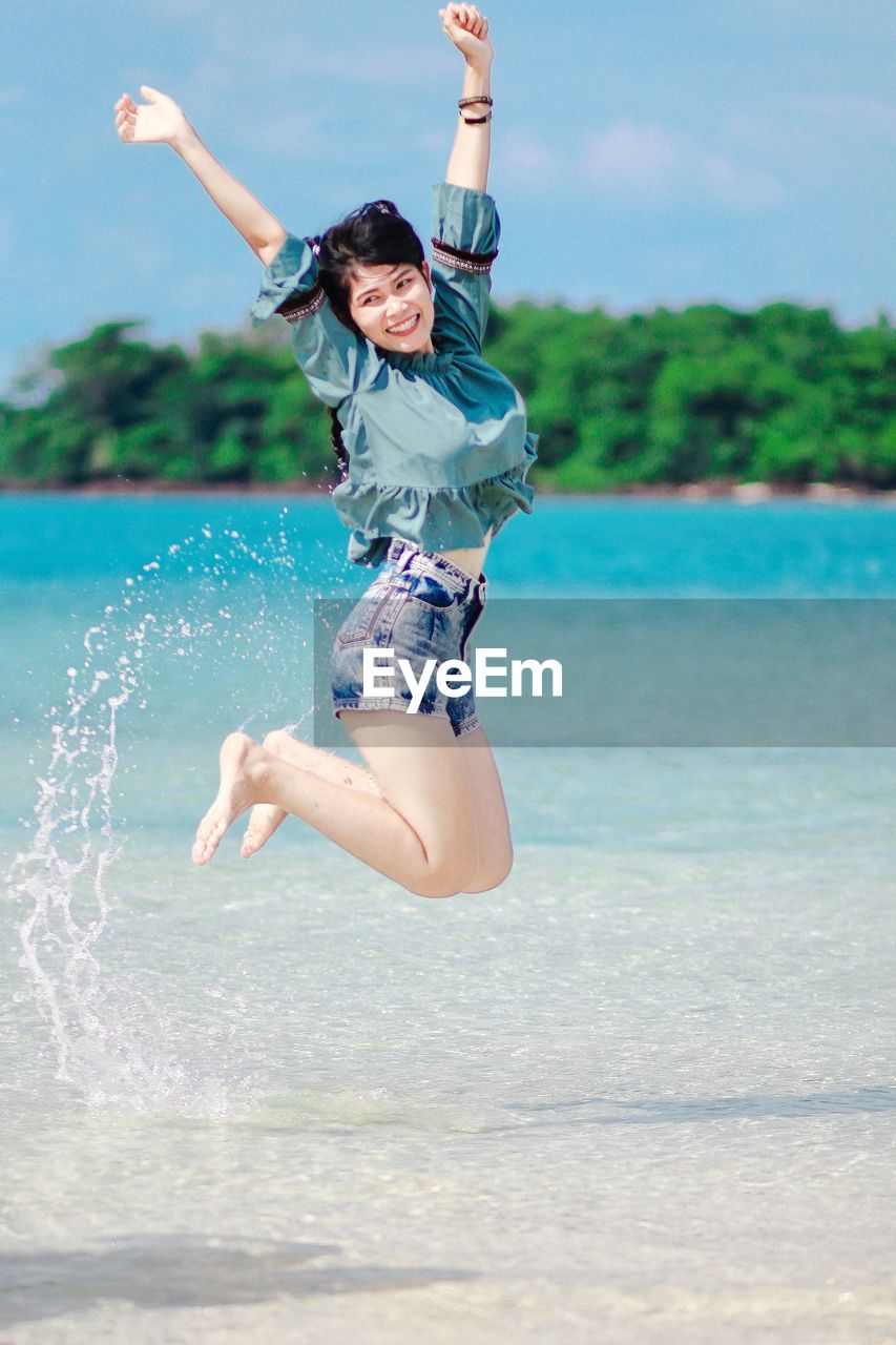 Full length of a young woman jumping in water