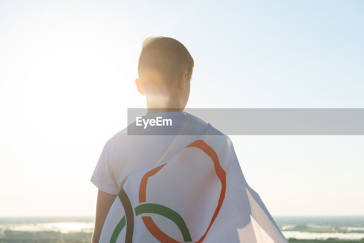 Rear view of man standing at beach against sky