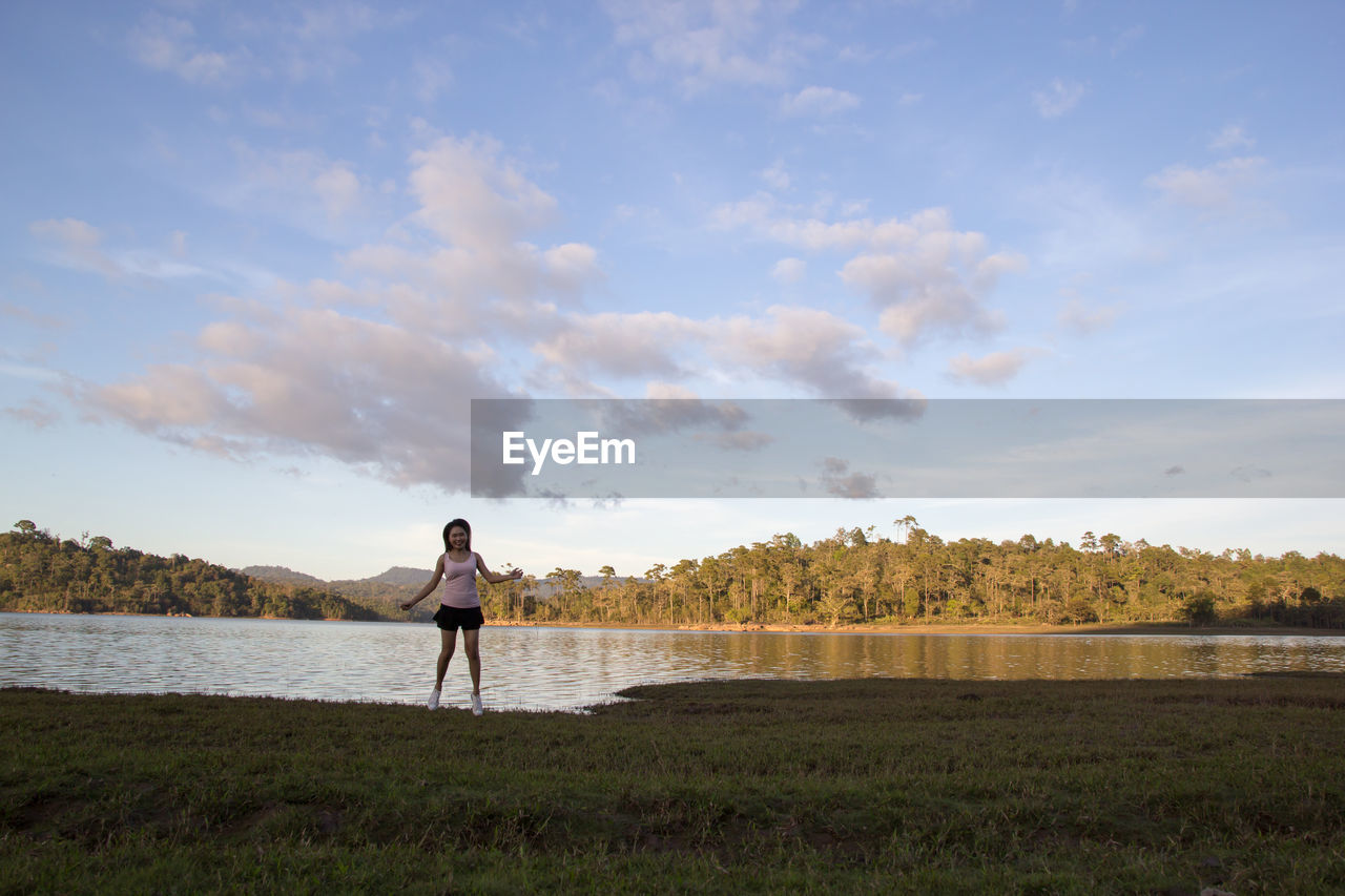 Full length of woman standing against lake and sky