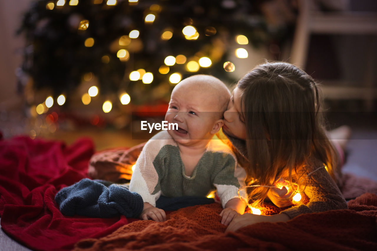 Girl and a younger sister, the baby is crying, and her sister feels sorry for her and comforts her.