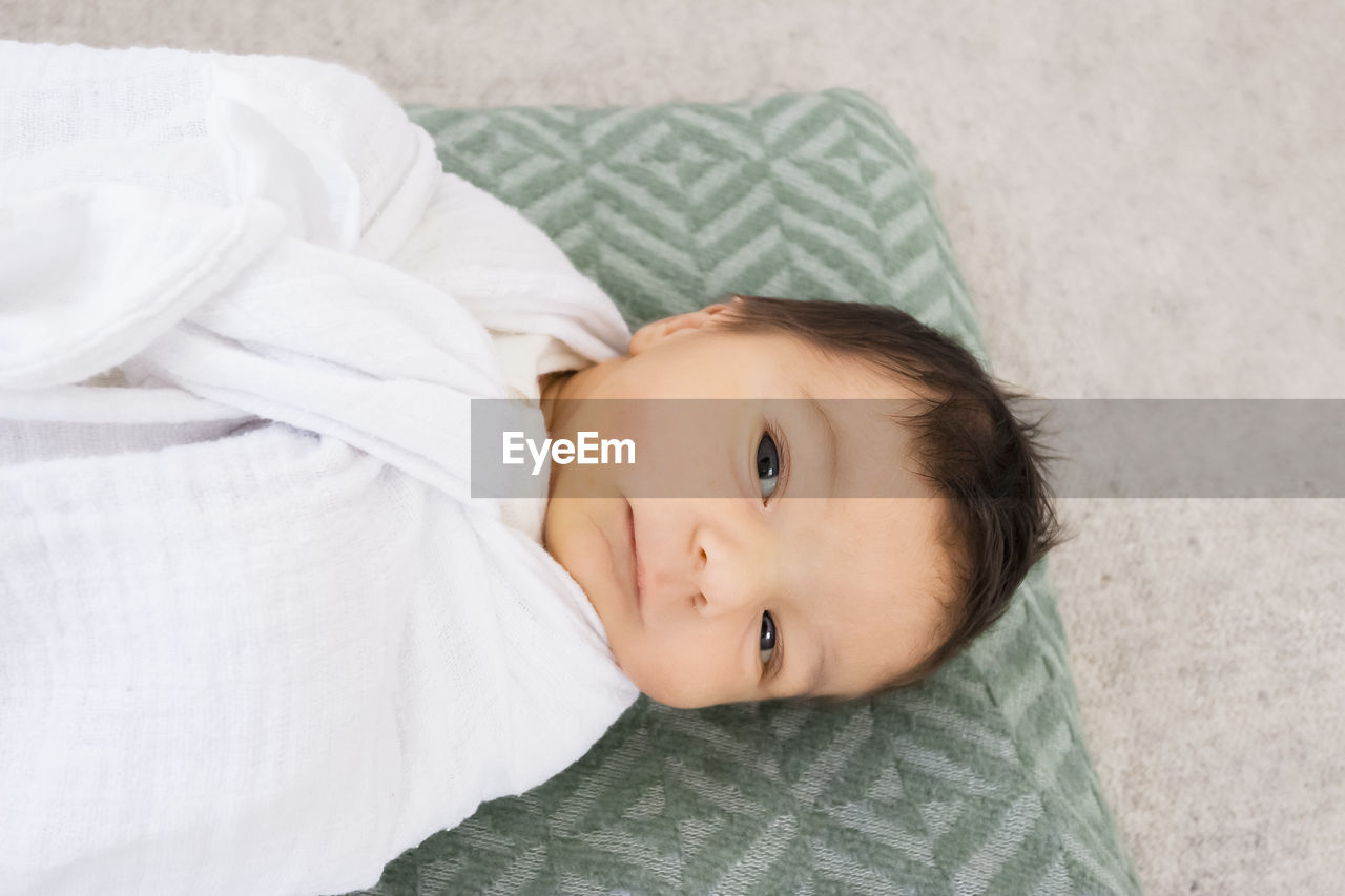 High angle portrait of cute baby girl lying on bed