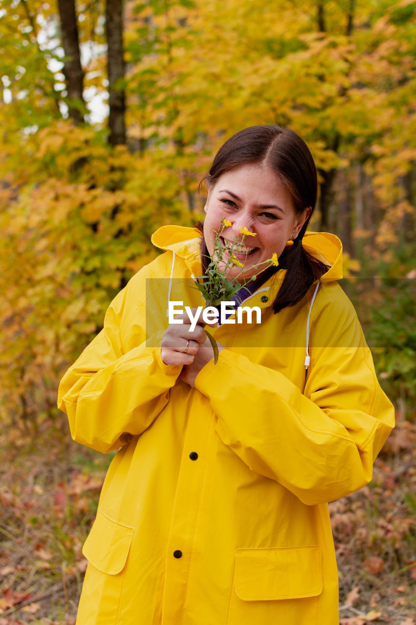 Cheerful young woman in a yellow raincoat and yellow boots poses for the camera. person
