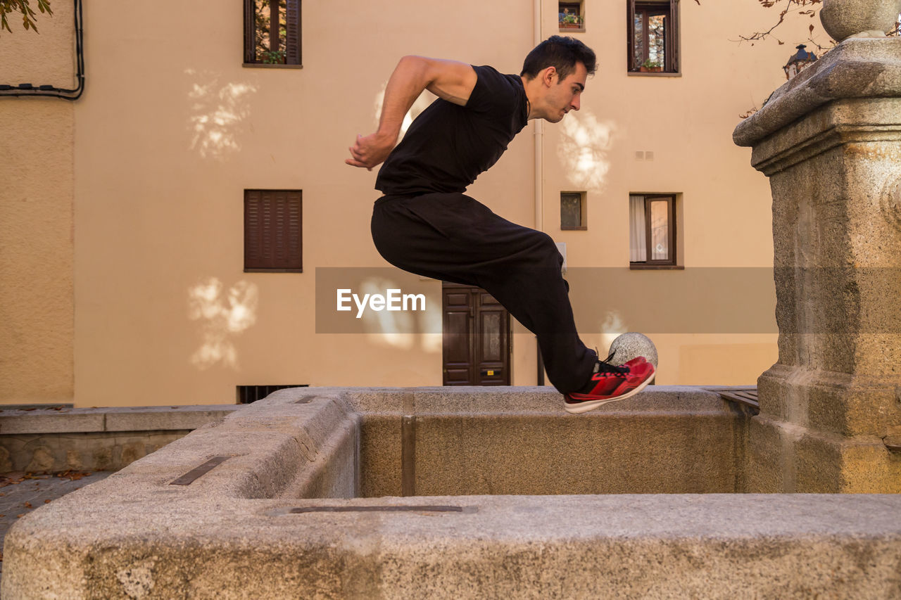 Full length of man jumping in artificial pond