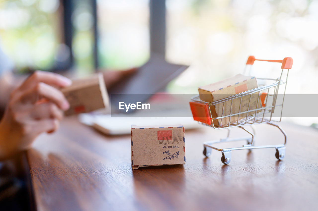 Close-up of small cardboard boxes with shopping cart on table
