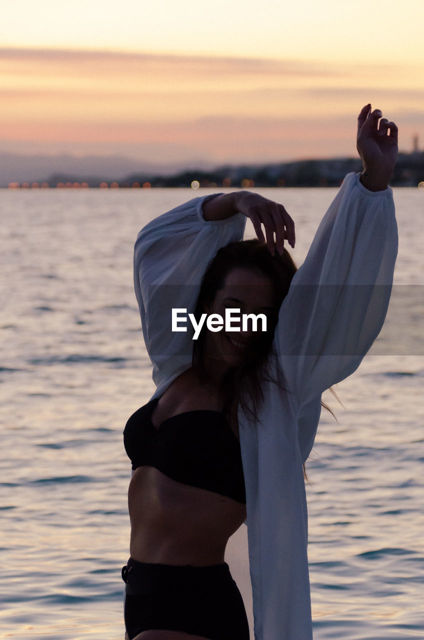 Woman standing at beach during sunset