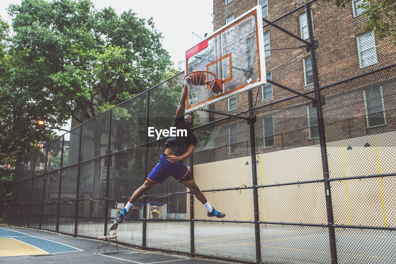 Young man scoring goal at basketball court