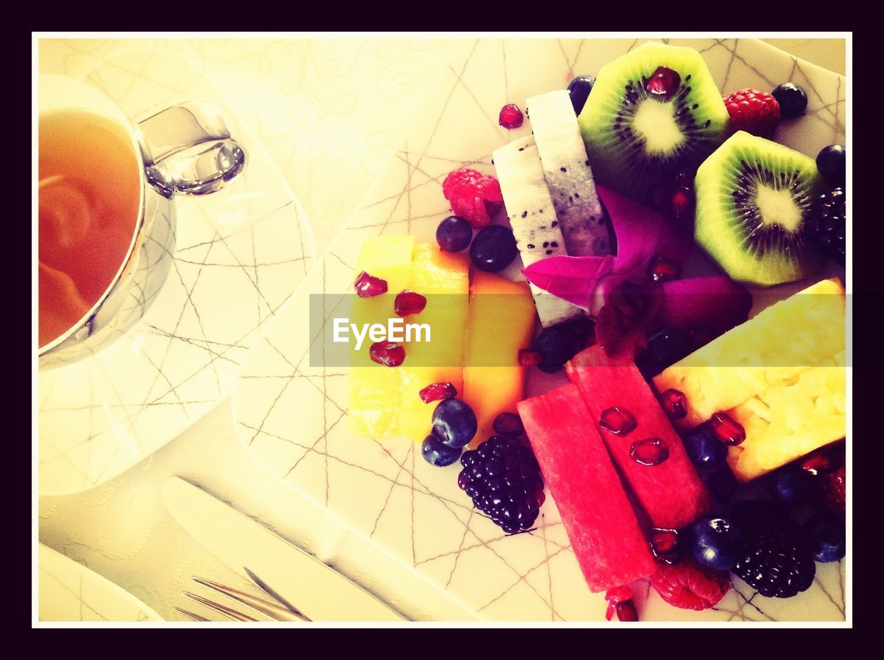 Close-up of sliced fruits with tea served on table