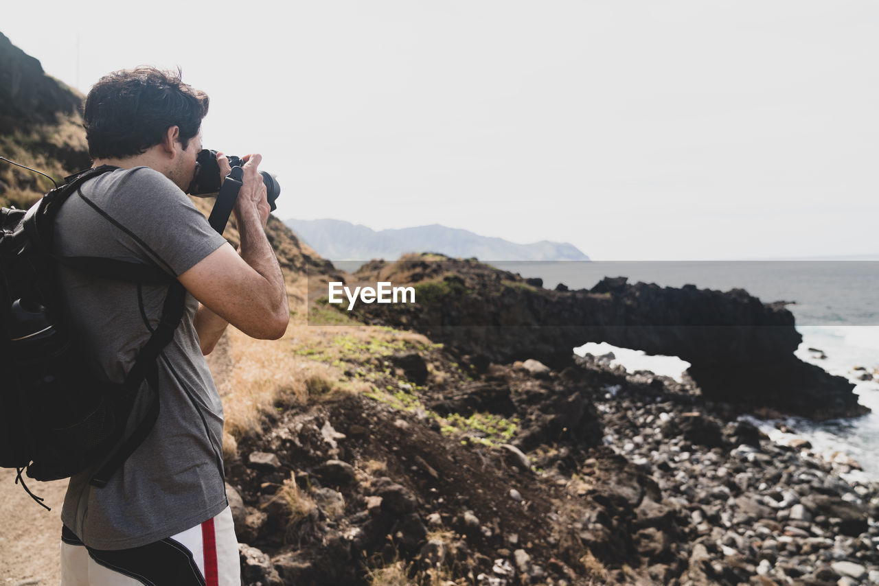 Male photographer at ka'ena point on oahu, hawaii