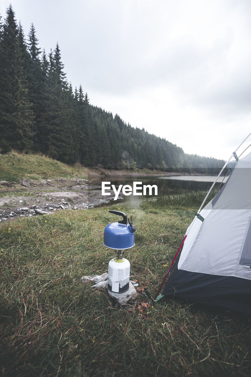 Camping stove and tent on field against sky