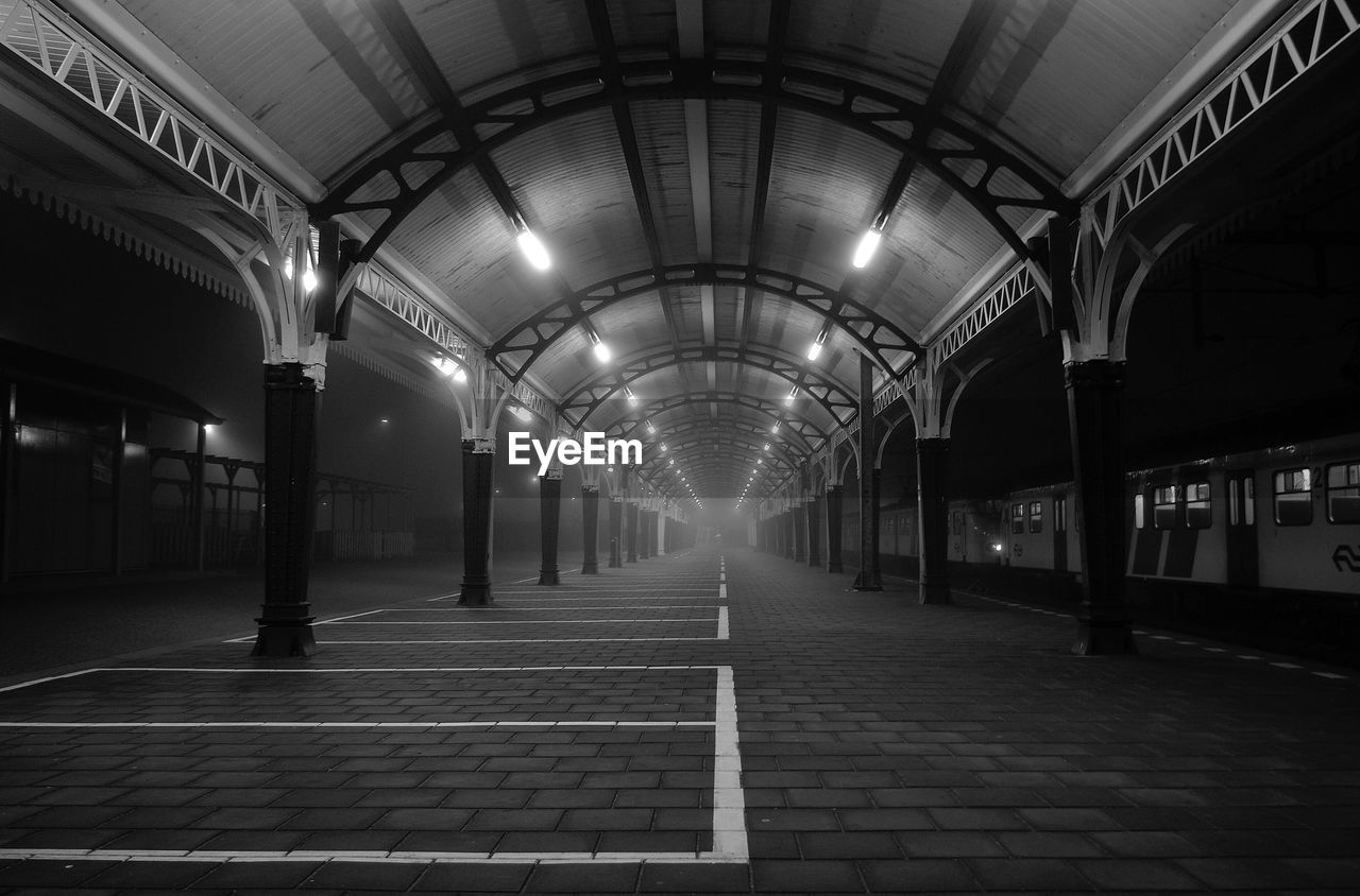 Empty covered railroad station platform at night