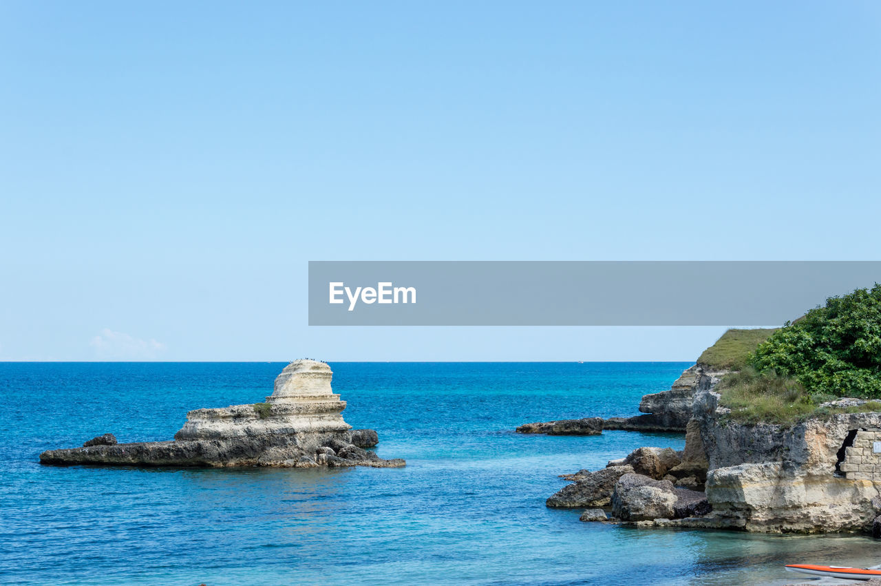 ROCKS ON SEA AGAINST CLEAR SKY