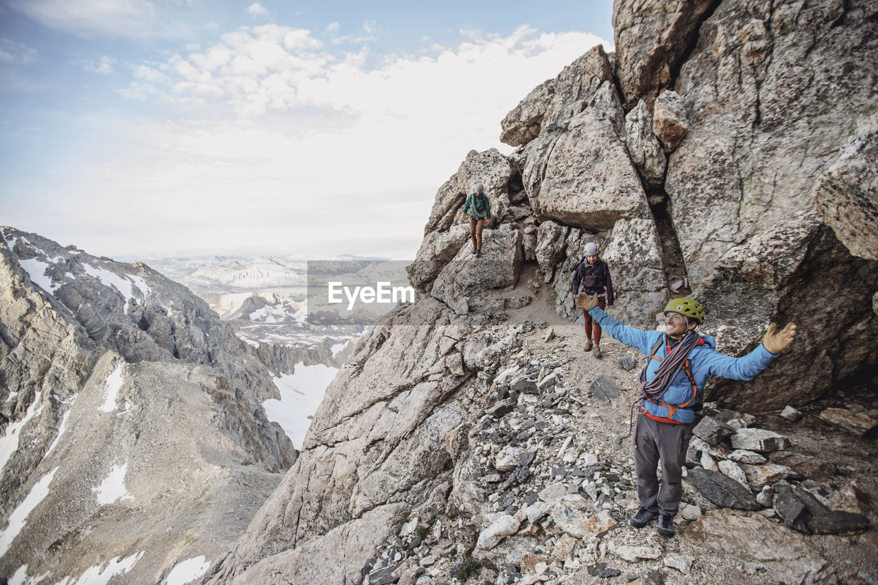 Climbing guide spreads his arms in wonder while taking in the view