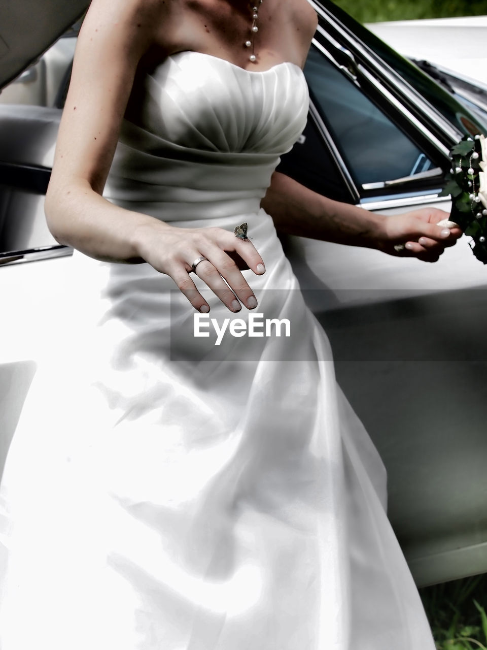 Midsection of bride wearing dress standing by car