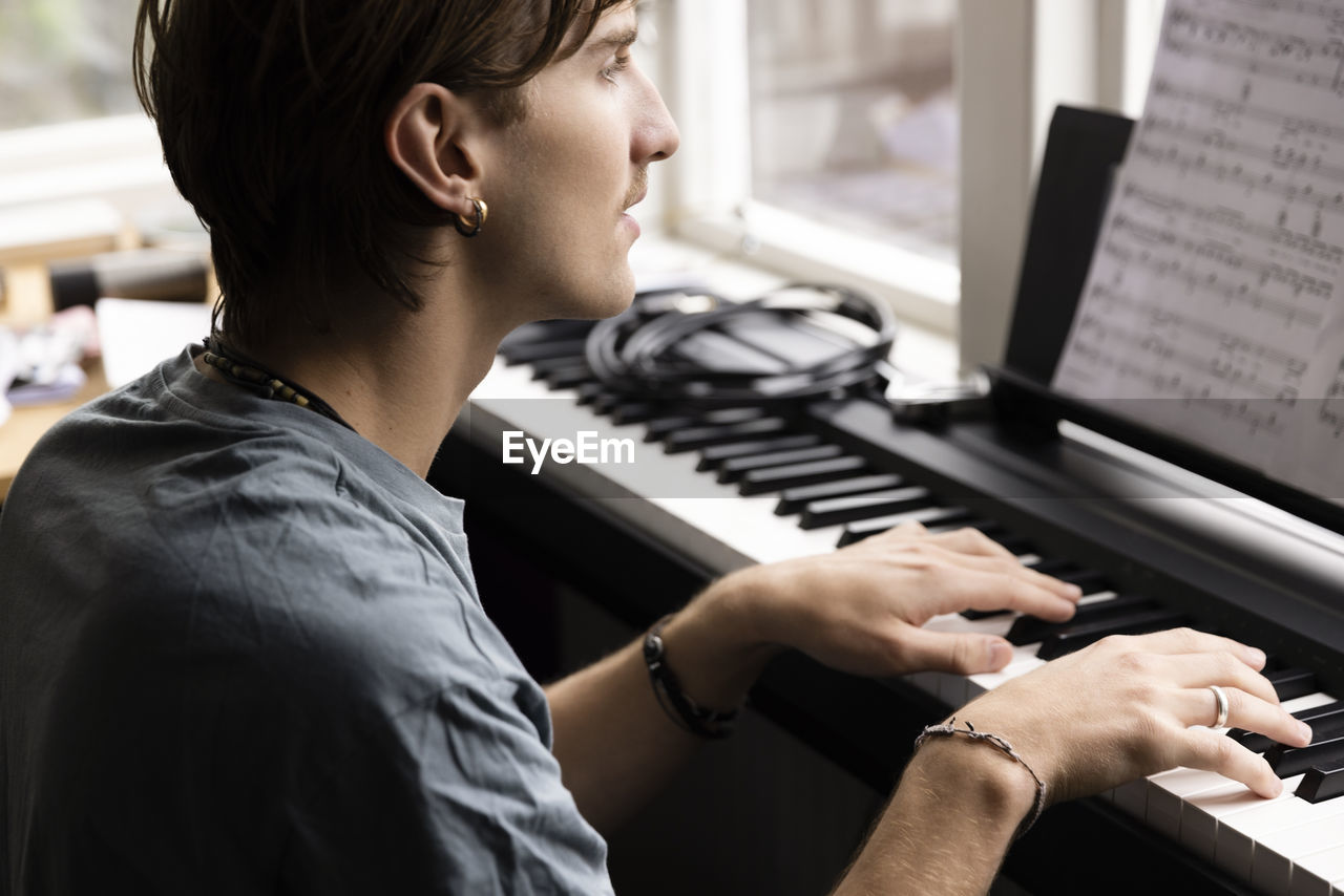 Concentrated young man practicing piano at home