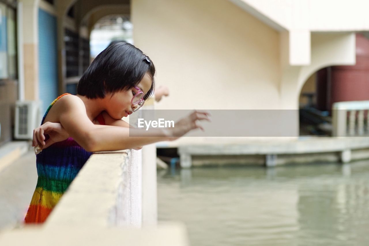 Cute girl looking down while standing by railing