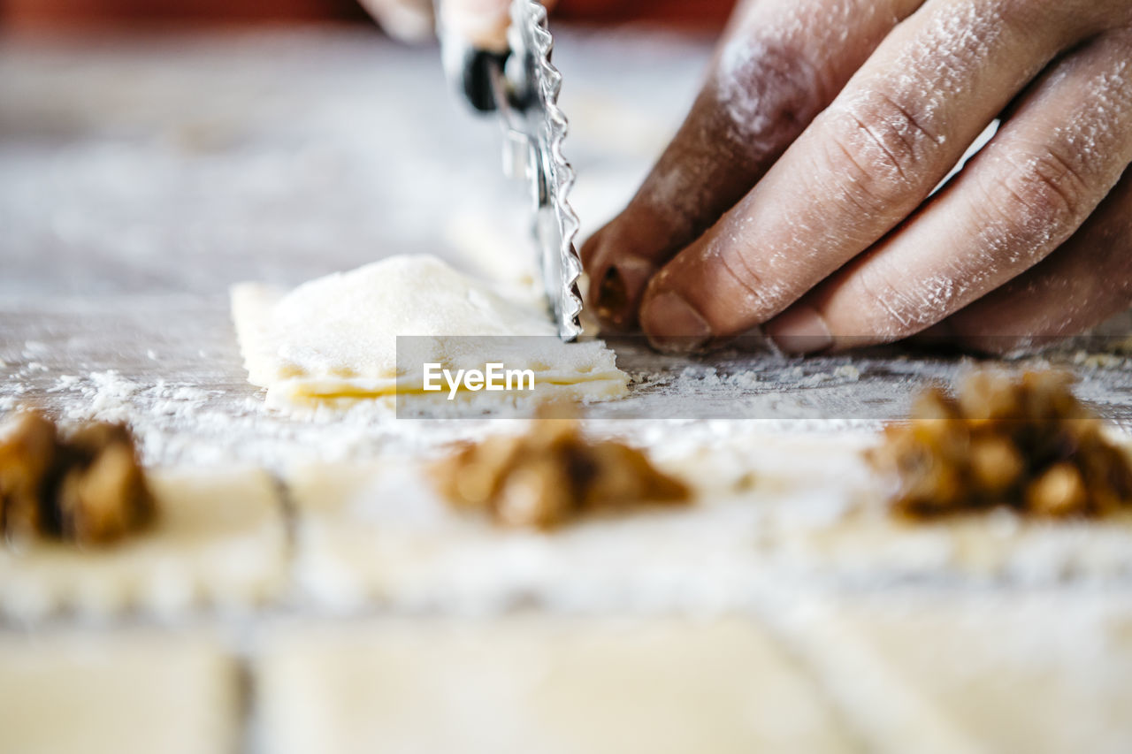 Cropped hands cutting ravioli dough