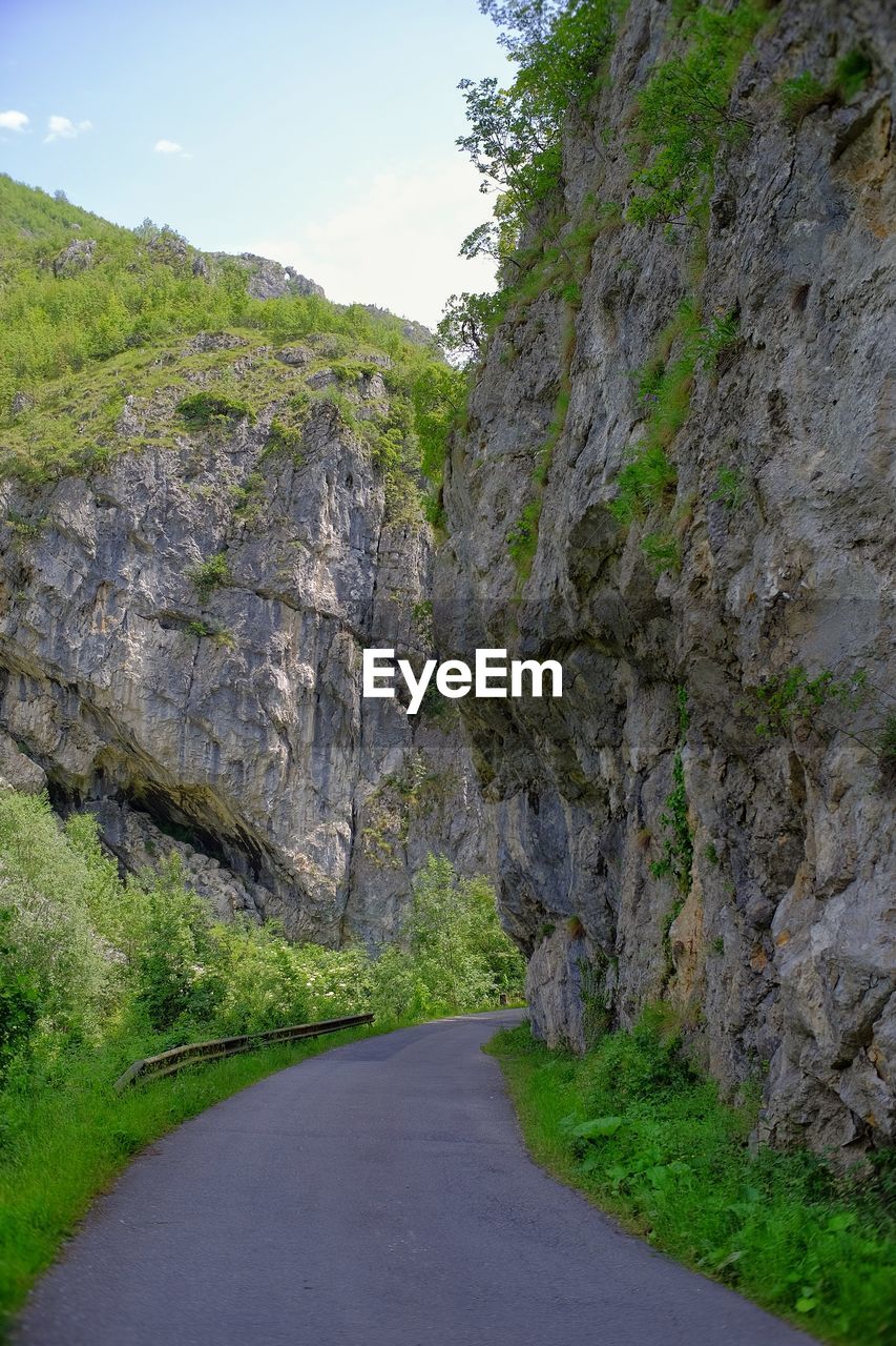 ROAD BY ROCK FORMATION AGAINST SKY