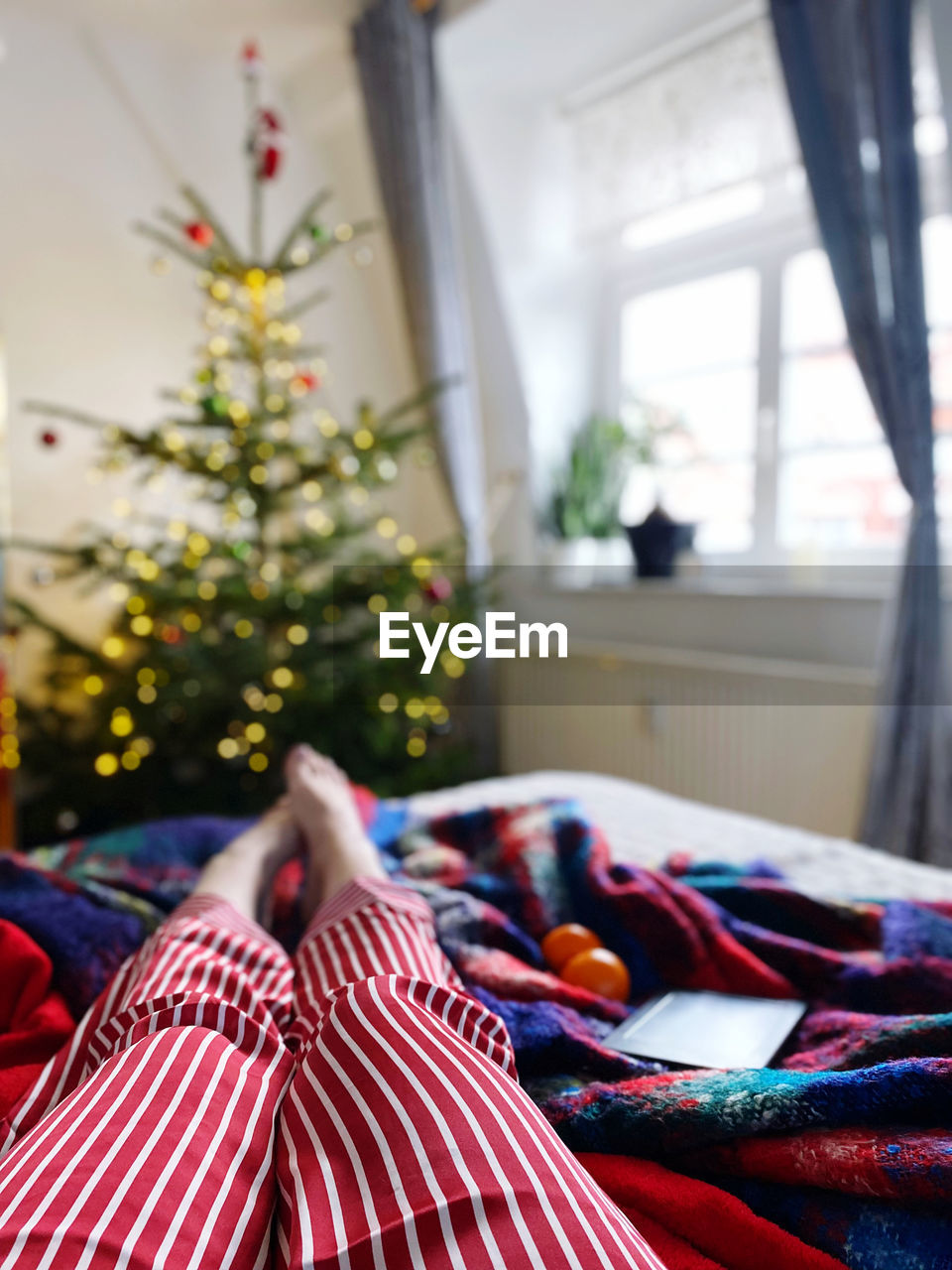 Low section of person woman relaxing on bed at home at christmas 