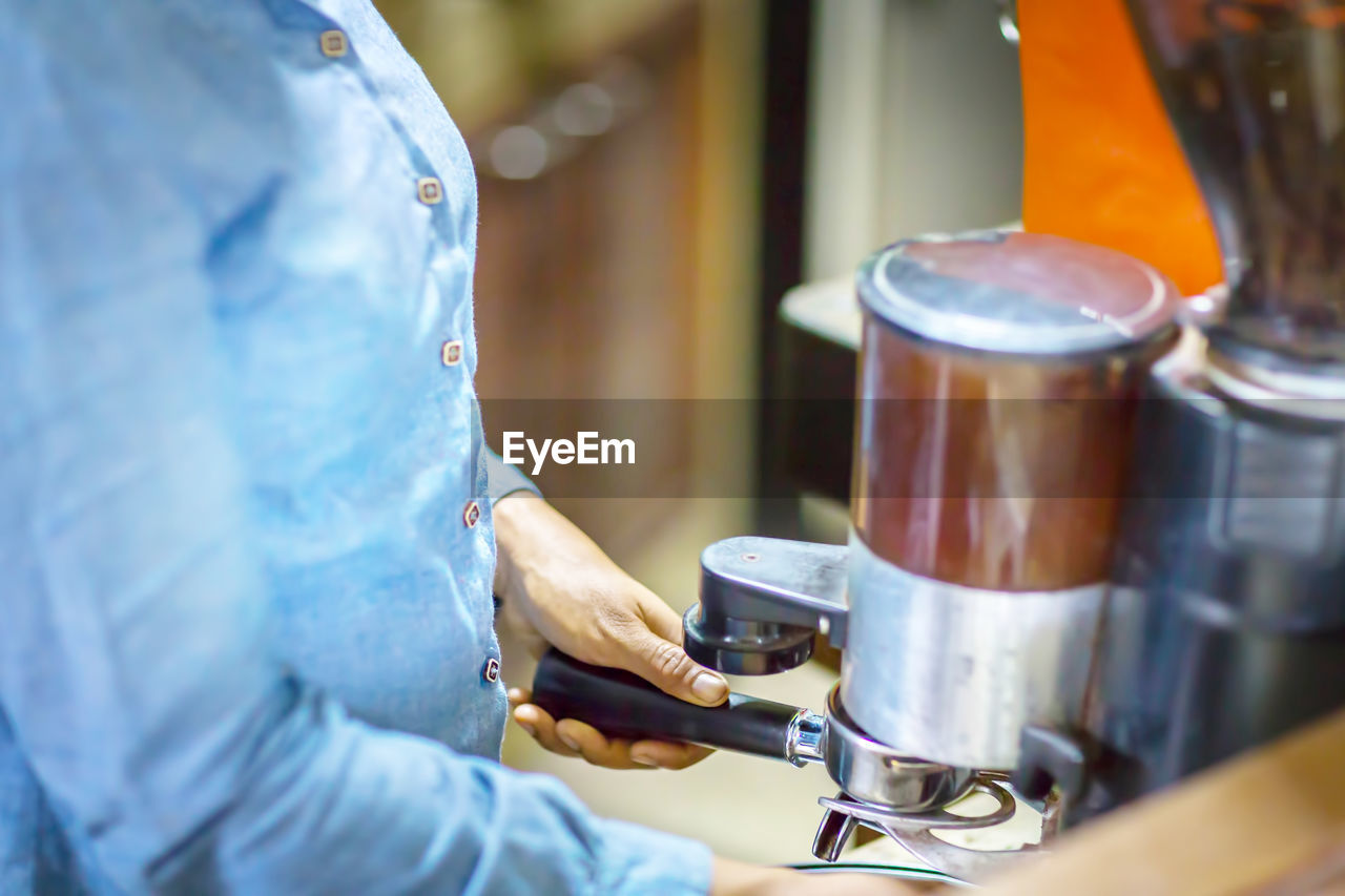 Close up barista is grinding freshly roasted by coffee grinder make beans into a powder.