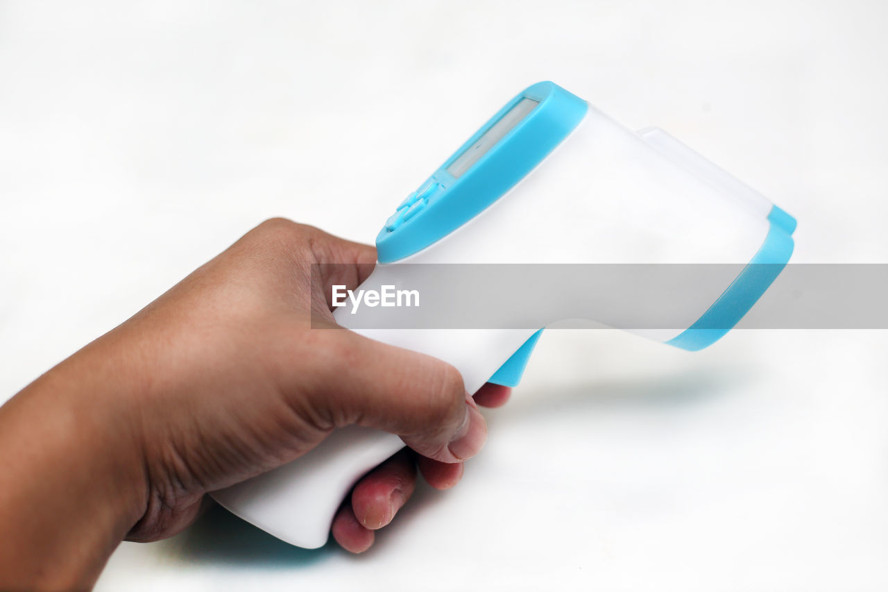 HIGH ANGLE VIEW OF HAND HOLDING PAPER AGAINST WHITE BACKGROUND