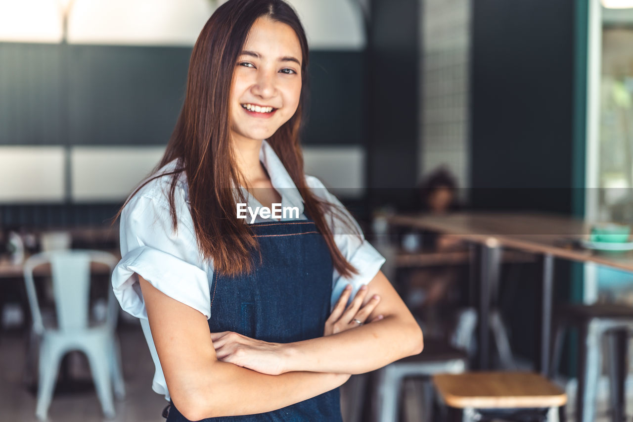 Portrait of smiling female owner standing in cafe