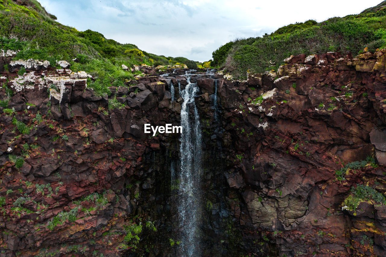 SCENIC VIEW OF WATERFALL ON ROCK FORMATION