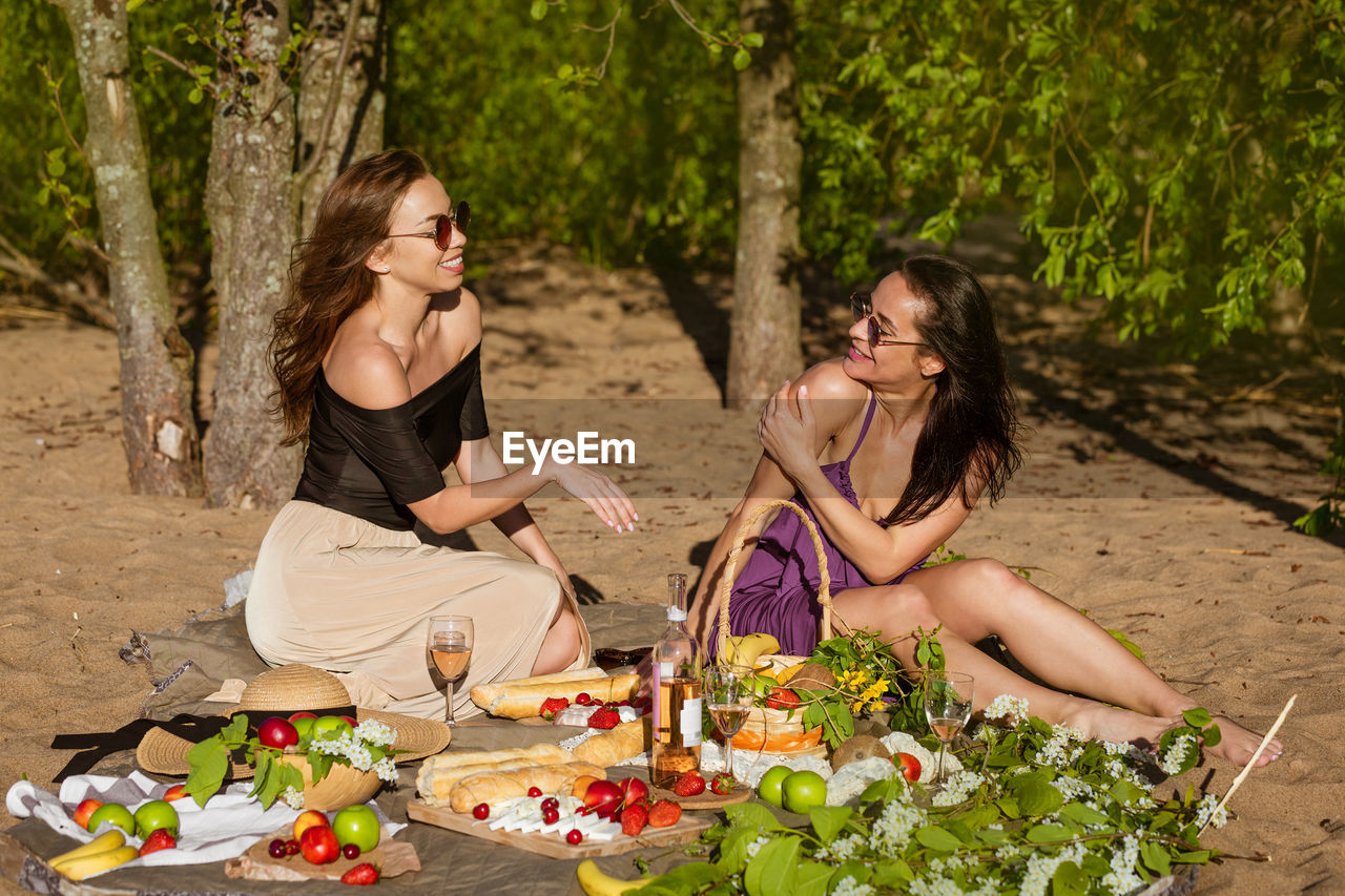 Two cute girls communicate on a picnic while sitting