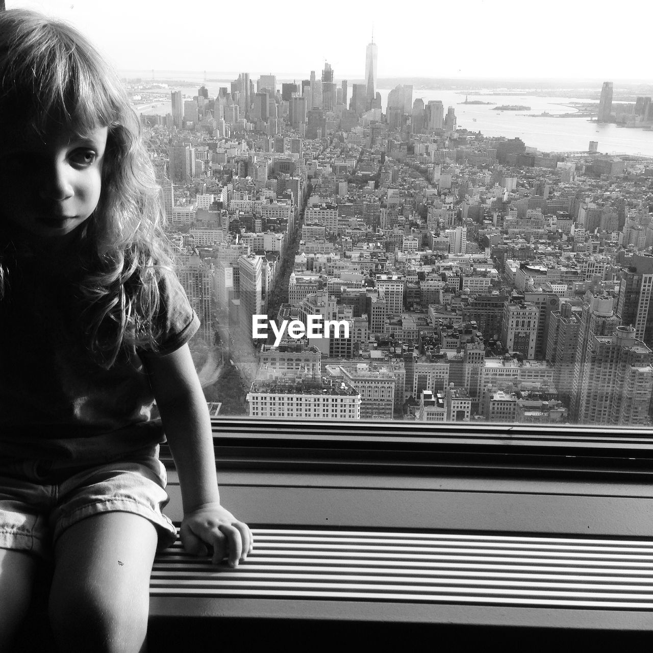 Girl sitting in window against buildings