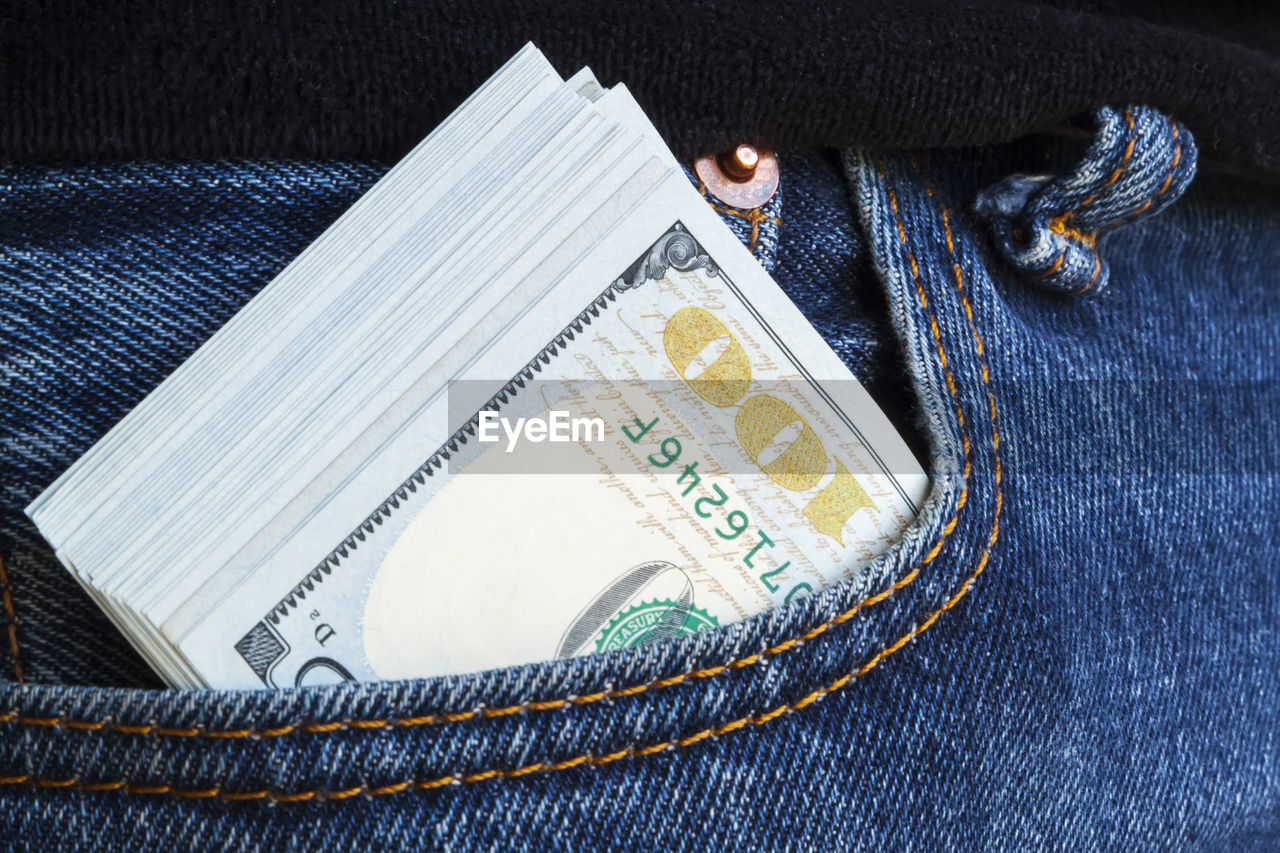 Hundred-dollar bills protrudes from pocket of jeans. all money earned is all given for credit