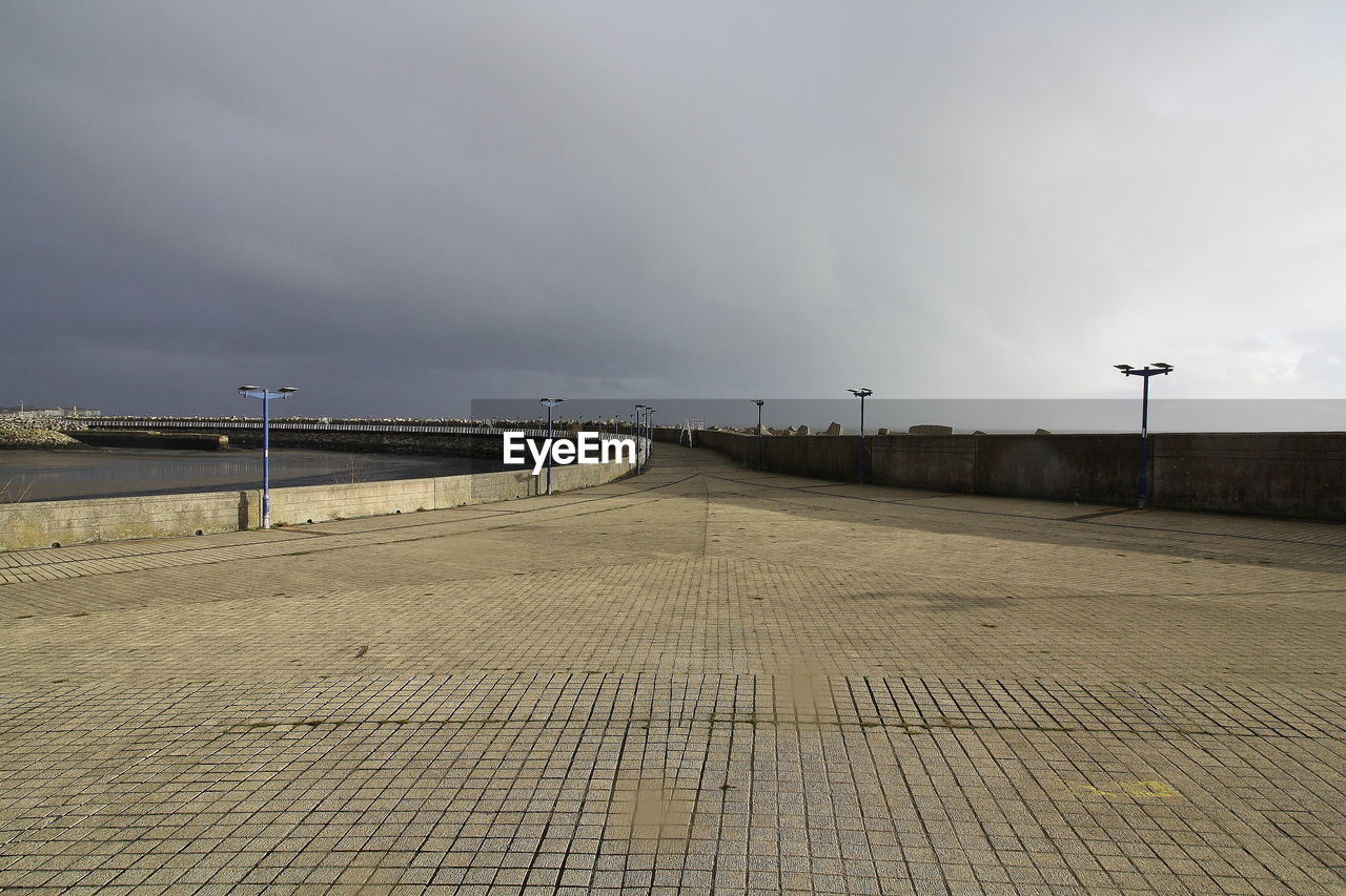 VIEW OF EMPTY FOOTPATH BY BRIDGE AGAINST SKY