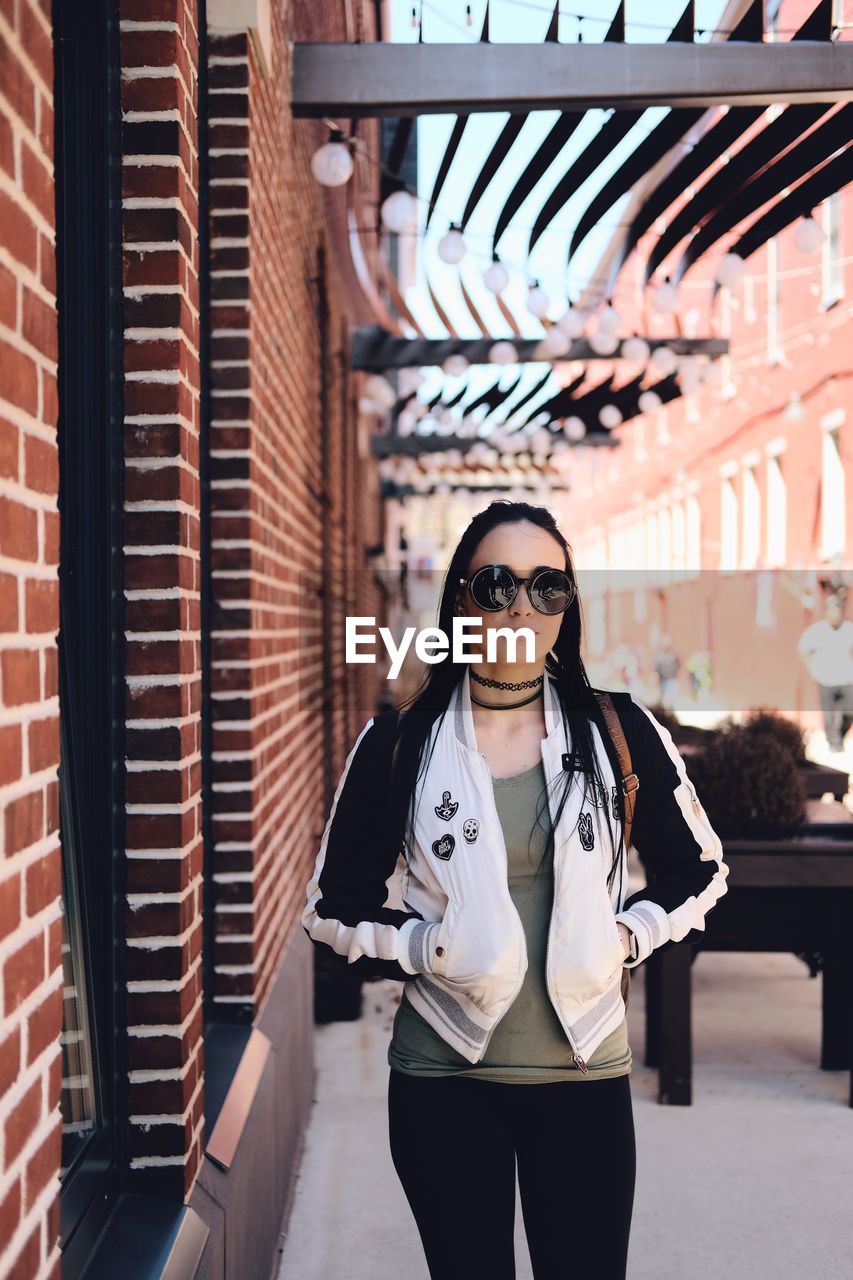 Portrait of woman in sunglasses standing on footpath