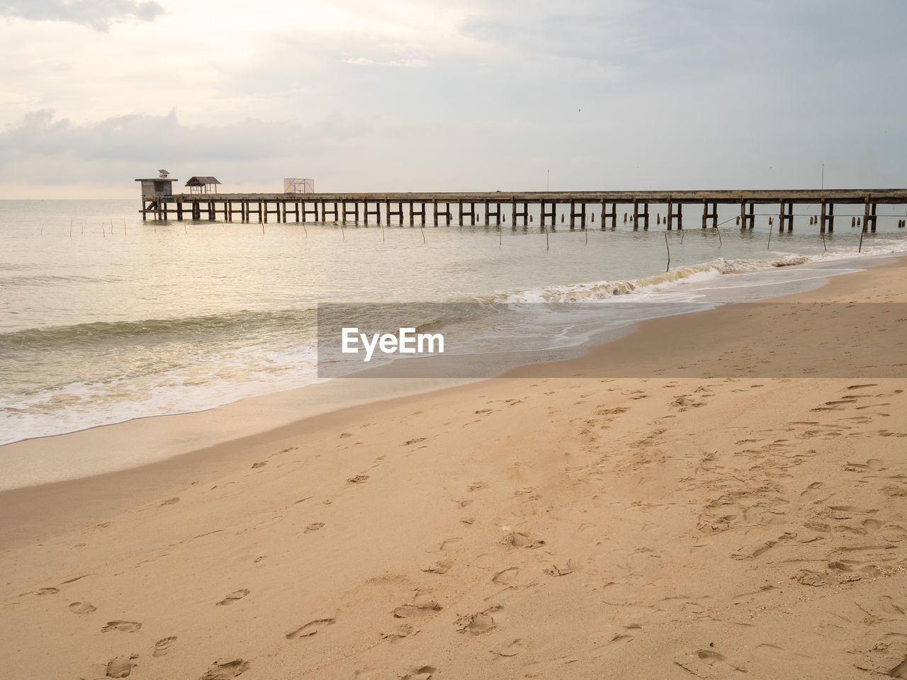 The sandy beach of the sea has wind waves, there are stone bridges that walk in the sea