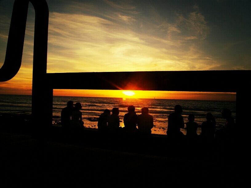 SILHOUETTE OF PEOPLE IN WATER AT SUNSET