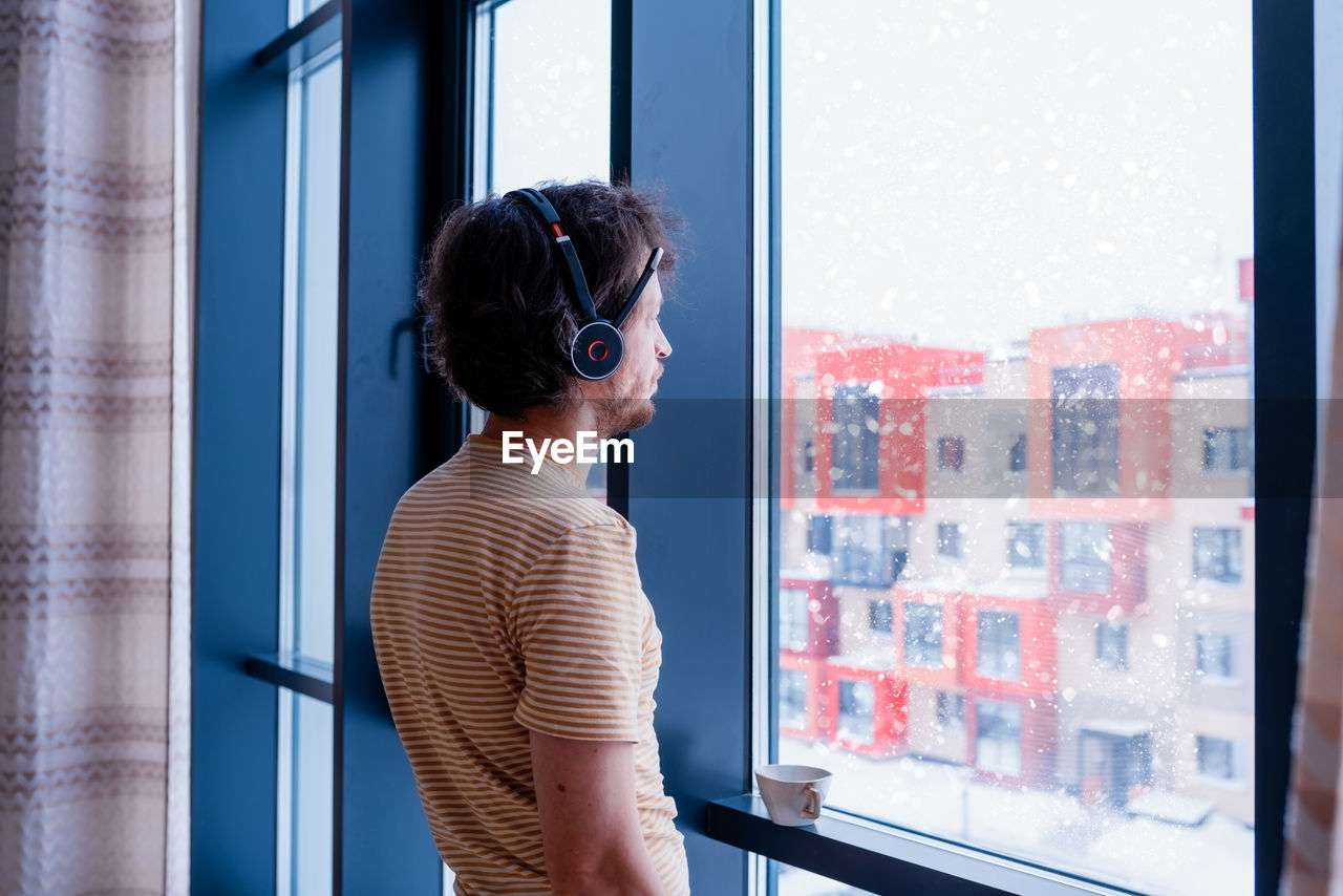 Adult programmer with a cup of tea talks to coworkers using a wireless headset 