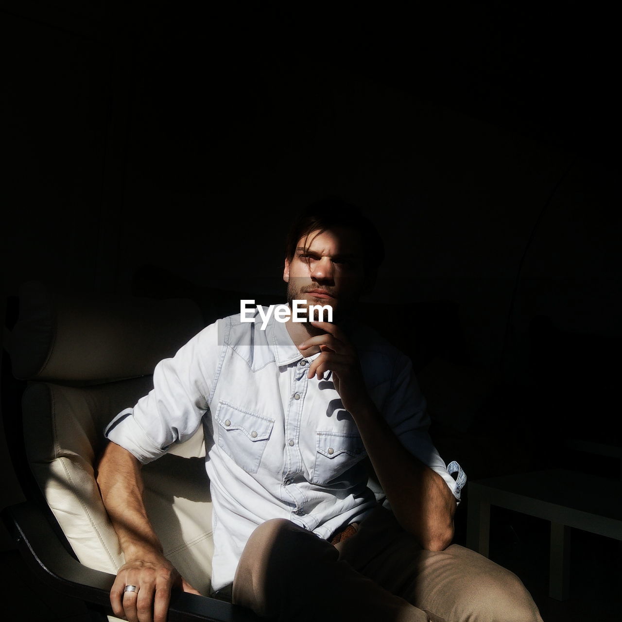 Sunlight falling on thoughtful man on chair