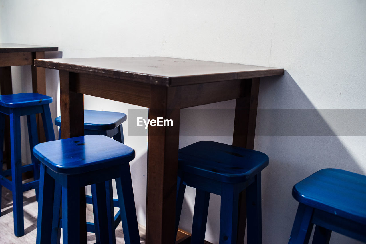 EMPTY CHAIRS ON TABLE AGAINST WALL