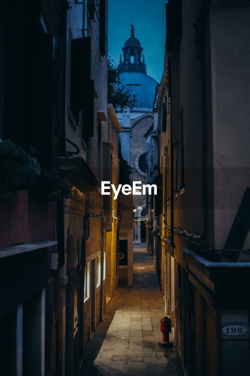 Alley amidst buildings in city at night