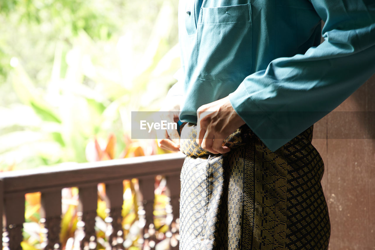 Midsection of man adjusting samping during ramadan festival 