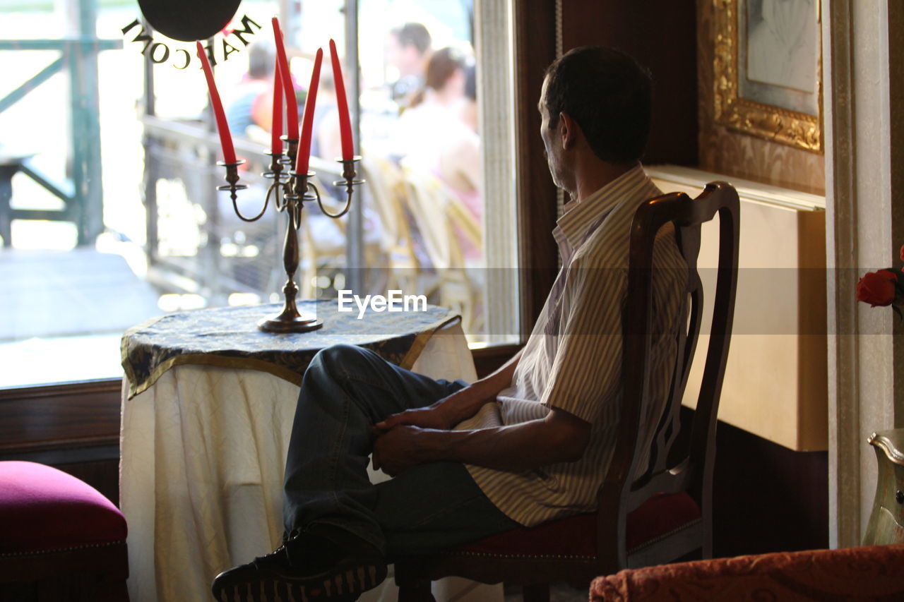 Side view of man sitting on chair in cafe