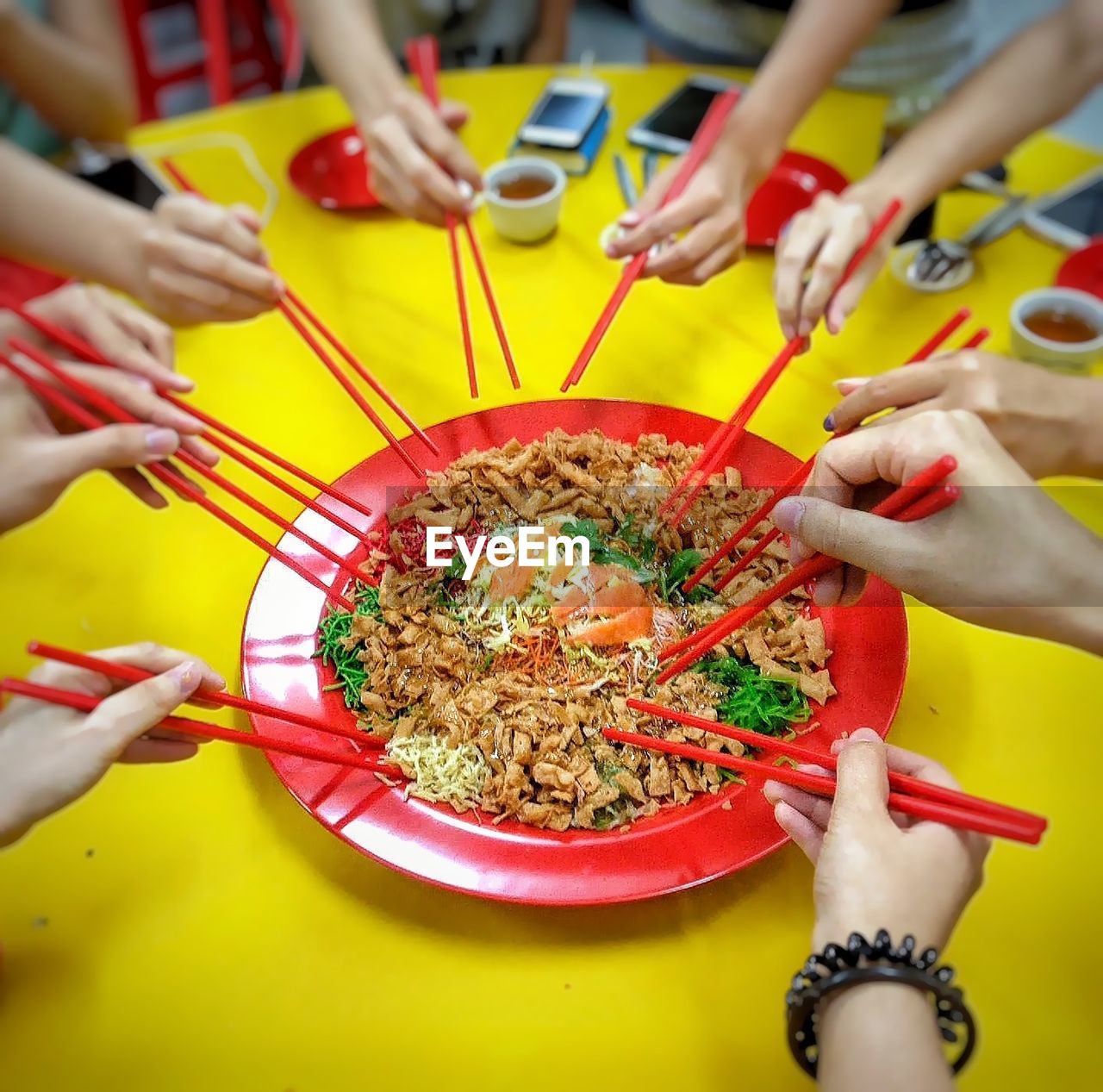 High angle view of cropped hands holding chopsticks over food served in plate